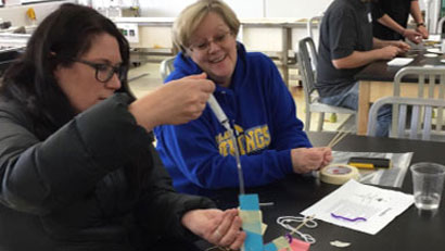 A woman with dark hair and a woman with blonde hair participate in an onsite professional development opportunity.