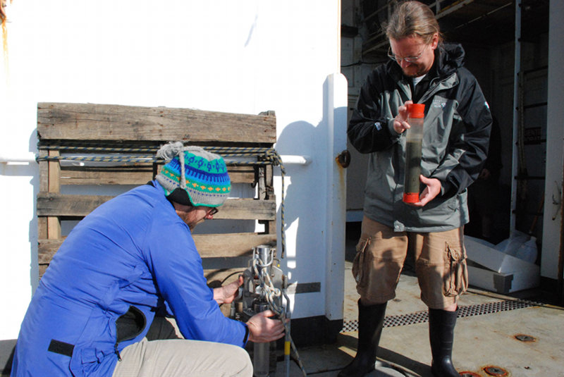 Mike Gray (right) holds a complete core sample from the monocore while Craig Robertson prepares it for the next deployment.