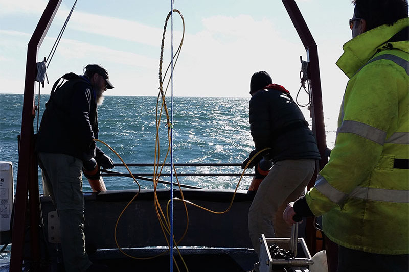 Photo of Matthew Lawrence and Brad Barr deploying the gradiometer (with Captain Mike Fleming at the winch) during one of the early test runs.