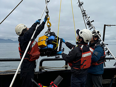 Researchers reach for the BlueROV, a small remotely operated vehicle used during the expedition.