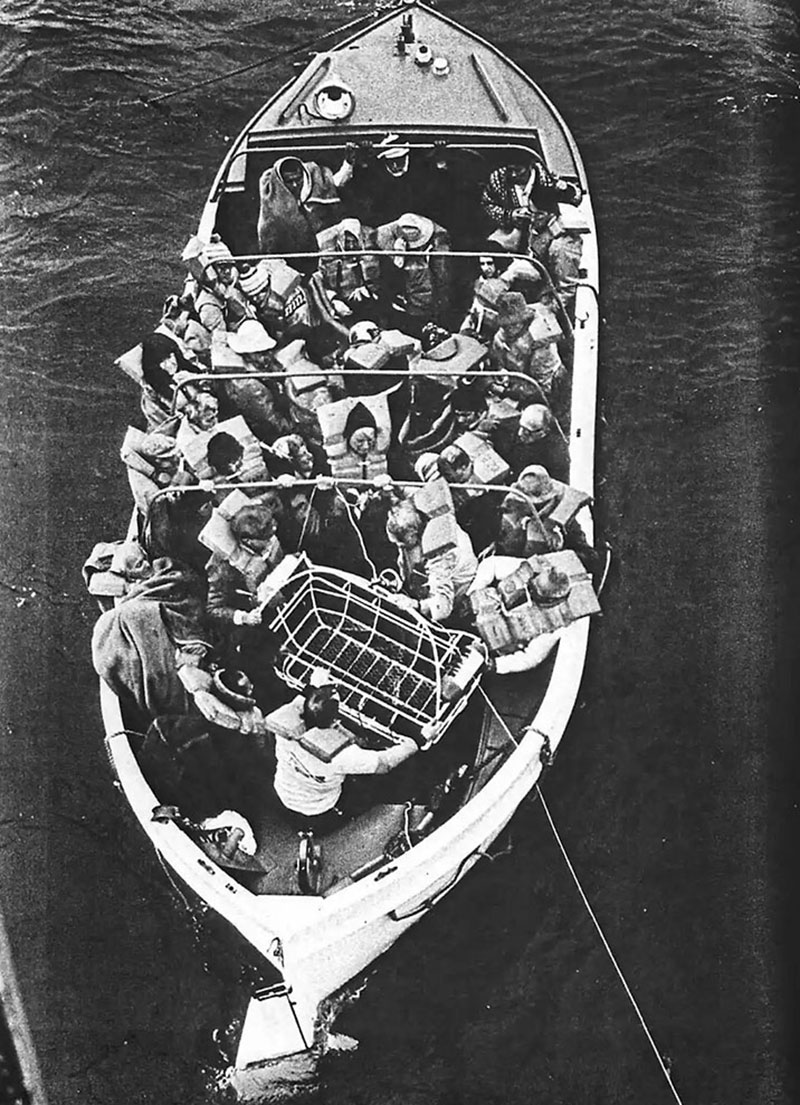 Prinsendam passengers in a life raft receive the USCG rescue basket for helicopter evacuation.