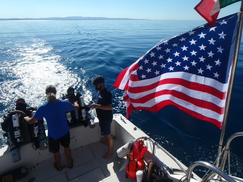 Final safety checks for closed-circuit divers preparing to investigate the site of a U.S. Army Air Force bomber off the coast of Italy. Safety checks are critical to maintaining safe diving practices and working gear.